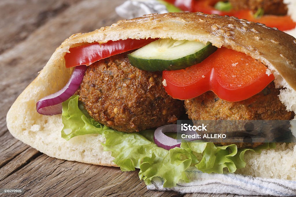 falafel with fresh vegetables in pita bread close-up falafel with fresh vegetables in pita bread close-up on wooden table horizontal Food Stock Photo