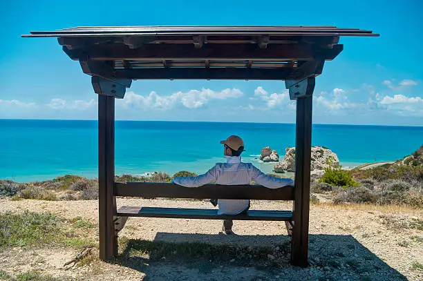 man sitting on bench looking at sea in Cyprus