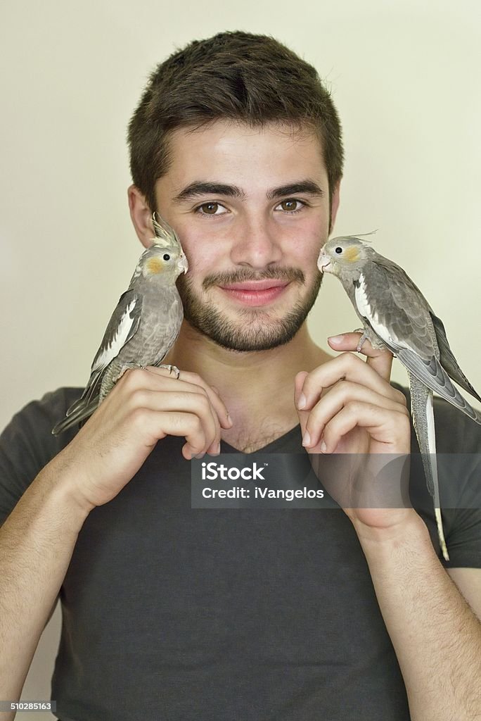 Junger Mann hält zwei Papageien auf jeder Seite - Lizenzfrei Männer Stock-Foto