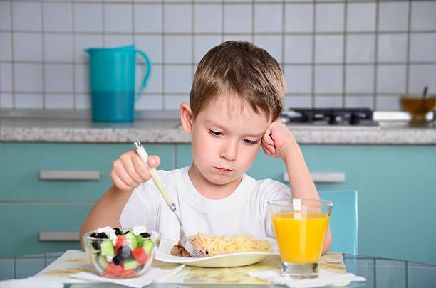 istock sad little boy sits at table and looking in plate 510287777