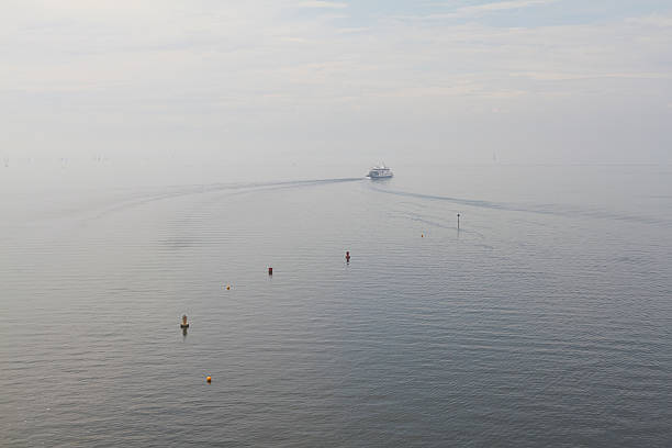 A boat on a lake moves into light fog.