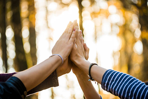 Four people joining their hands together stock photo