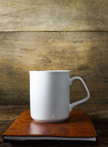 cup of coffee and book on old wood background
