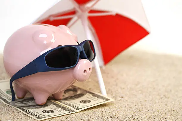 Photo of Piggy bank on towel of greenback hundred dollars with sunglasses