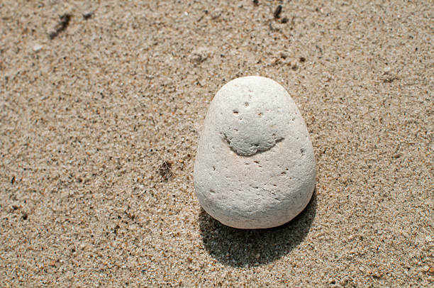 Naturally made image of smile on sea pebble stone on sand background