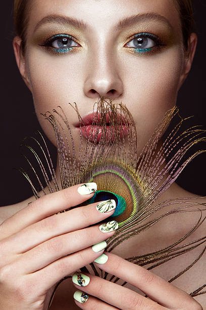 hermosa chica con manicura de diseño y pluma pavo real - stage makeup peacock make up feather fotografías e imágenes de stock