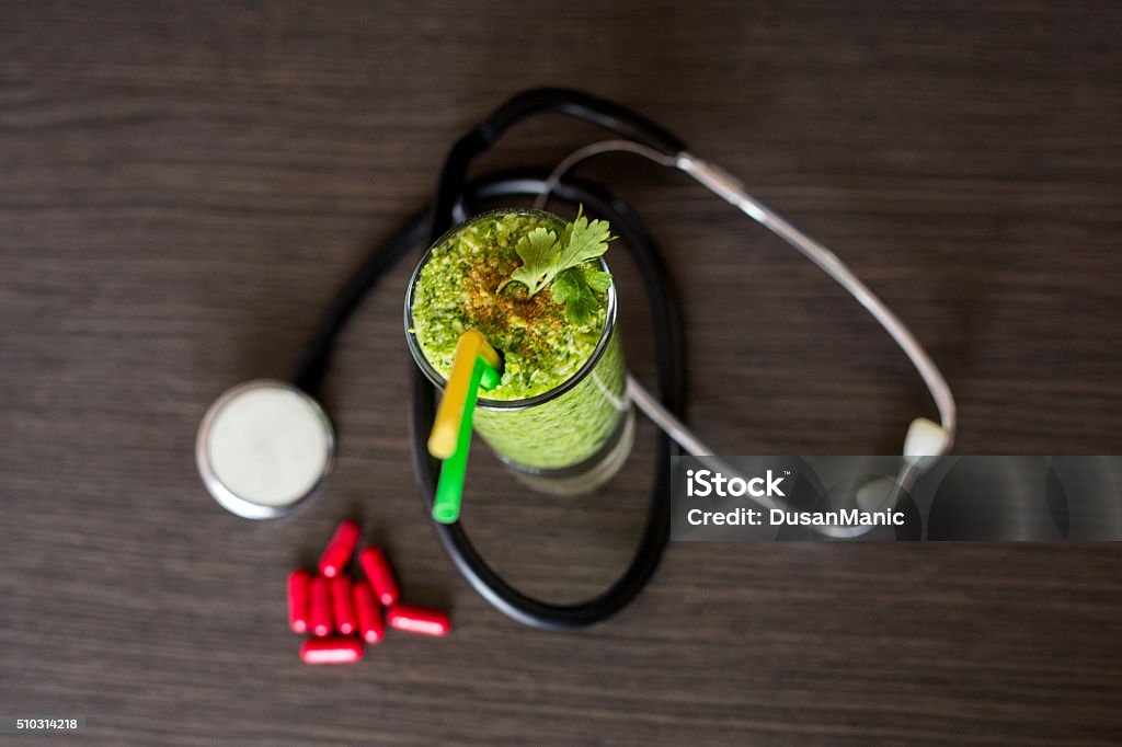 Healthy green smoothie and cholesterol diet concept Alternative medicine stethoscope and  green smoothie on wooden table Alternative Therapy Stock Photo