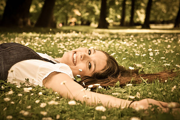 Detail of young woman lying in fresh green grass with flowers - above view