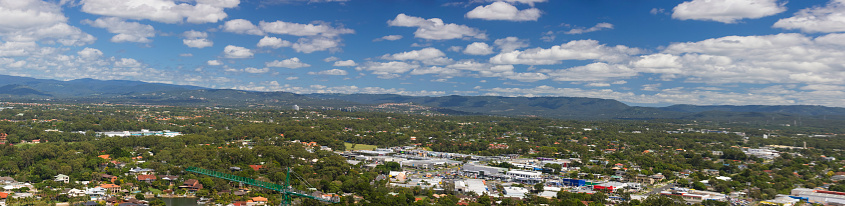 Panorama of a industrial area of a town and a forest and mountains under a cloudy sky
