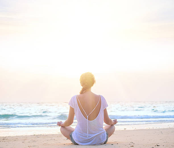 istock woman practicing yoga at sunrise beach 510329126