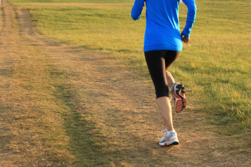 Runner athlete  running on grassland trail . woman fitness jogging workout wellness concept.
