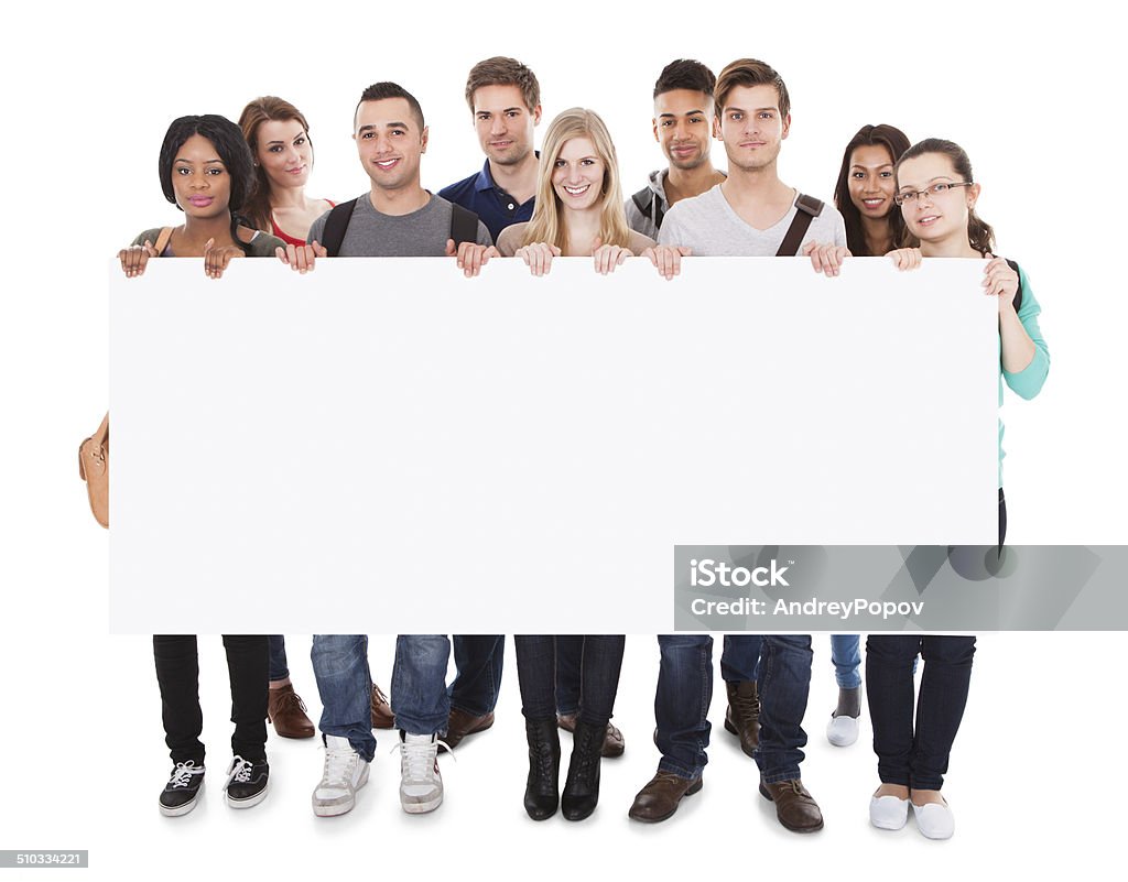 College Students Displaying Blank Billboard Full length portrait of confident multiethnic college students displaying blank billboard against white background Banner - Sign Stock Photo