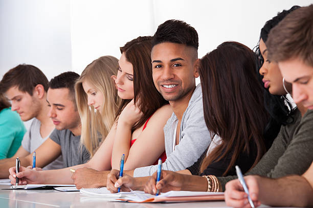 istock Confident Student Sitting With Classmates Writing At Desk 510338563