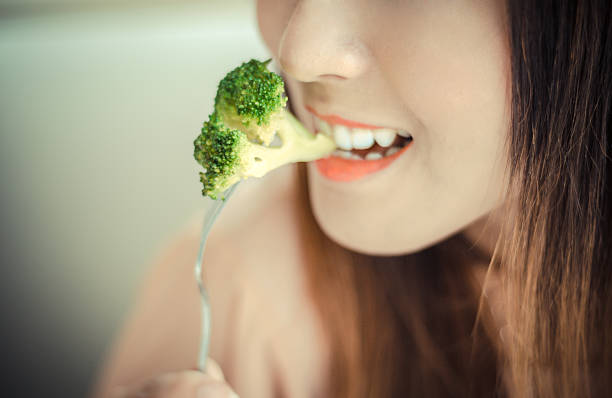 istock happy smiling  woman eating broccoli 510352255