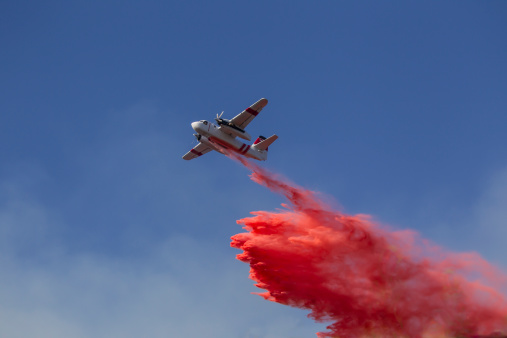 A small fire fighting aircraft drops fire retardant on a near by brush fire.