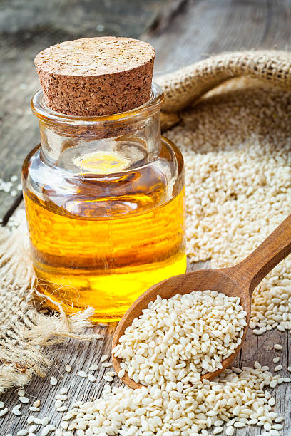 bottle of oil sesame seeds in sack on old table stock photo
