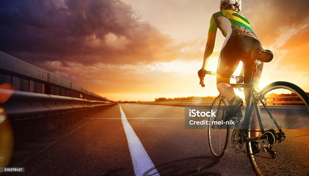 Mountain bike riding a bike a la puesta del sol en la autopista - Foto de stock de Bicicleta de carreras libre de derechos