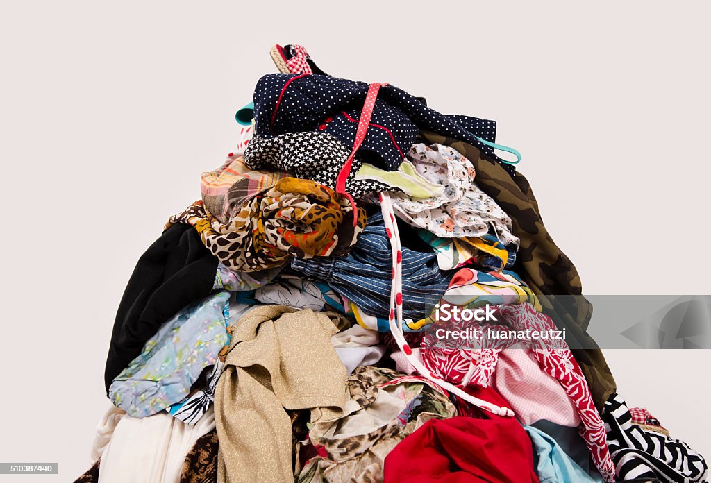 Big pile of clothes and accessories thrown on the floor. Untidy cluttered wardrobe with colorful clothes and accessories on the ground. Clothing Stock Photo