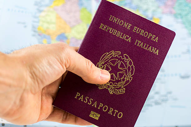 hand holds an Italian Passport hand holds an Italian passport with a blurred map in the background schengen agreement stock pictures, royalty-free photos & images