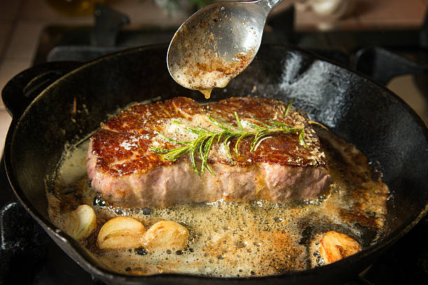 Strip Loin Steak Preparing beef strip loin steak on an iron pan. cooking with garlic stock pictures, royalty-free photos & images