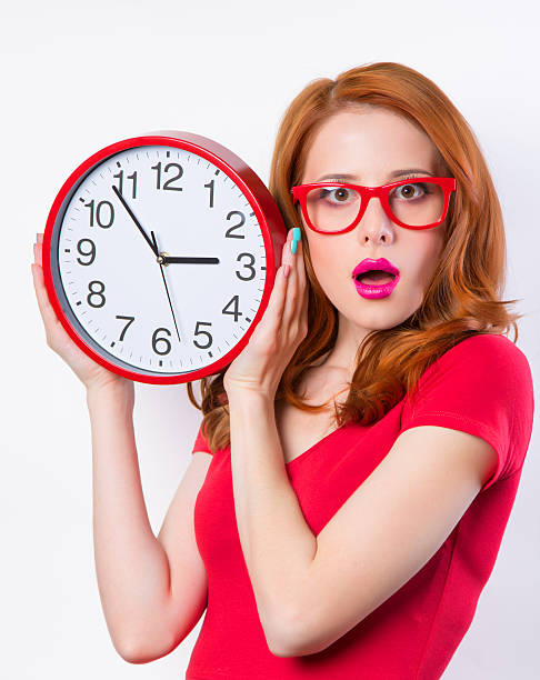 istock Surprised redhead girl with huge alarm clock on light background 510393661