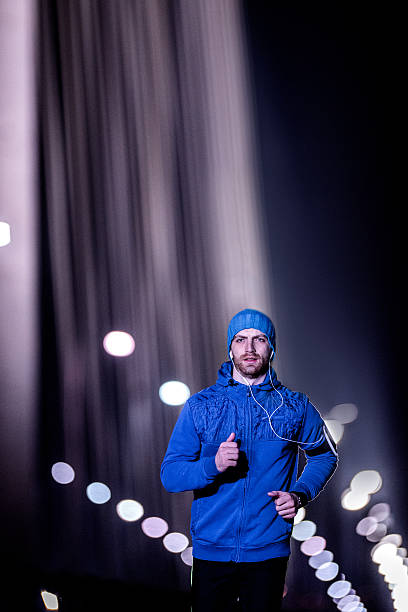 istock Young man jogging through the city at night 510394484