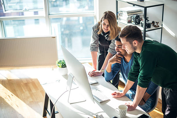 Doing business together Three coworkers working on a computer in the office. small stock pictures, royalty-free photos & images