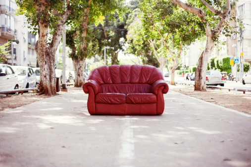 red vintage leather sofa standing on the street