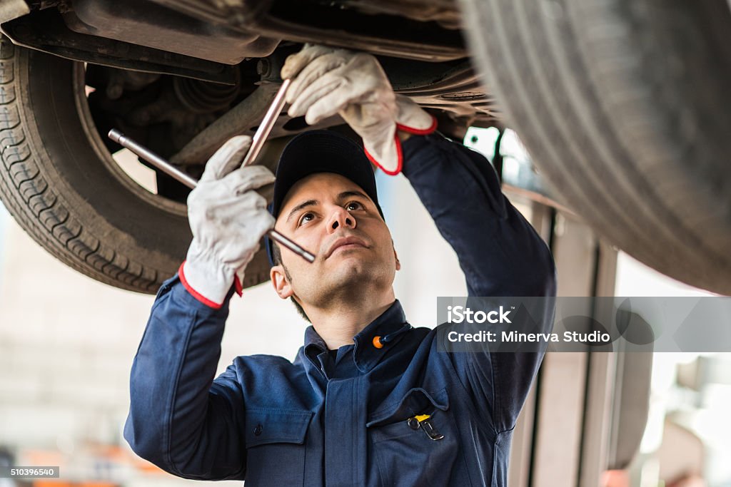 Mechanic repairing a lifted car Portrait of a mechanic repairing a lifted car Auto Mechanic Stock Photo
