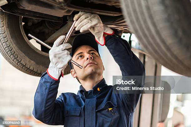 Mechanic Repairing A Lifted Car Stock Photo - Download Image Now - Auto Mechanic, Mechanic, Auto Repair Shop