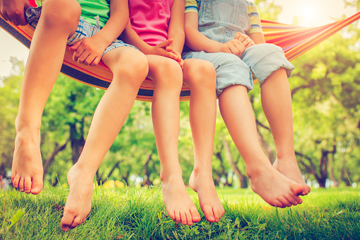 Smiling child peeking from colorful hammock. Outdoor relaxation and joy concept. Summer leisure scene. Design for greeting card, postcard