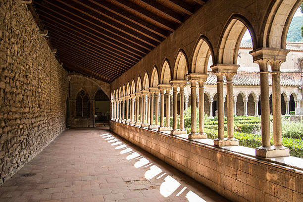 Lower part of the majestic interior of the cloister of Ambronay Abbey illuminated by night. This photo was taken at the Notre Dame d'Ambronay Abbey famous local monument in the French village of Ambronay, in the Ain department in the Auvergne-Rhone-Alpes region.