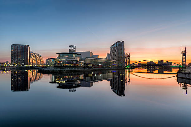Orange Sunrise At Salford Quays With Reflections. A winter orange sunrise at Salford Quays with clear reflections in the water. manchester england stock pictures, royalty-free photos & images
