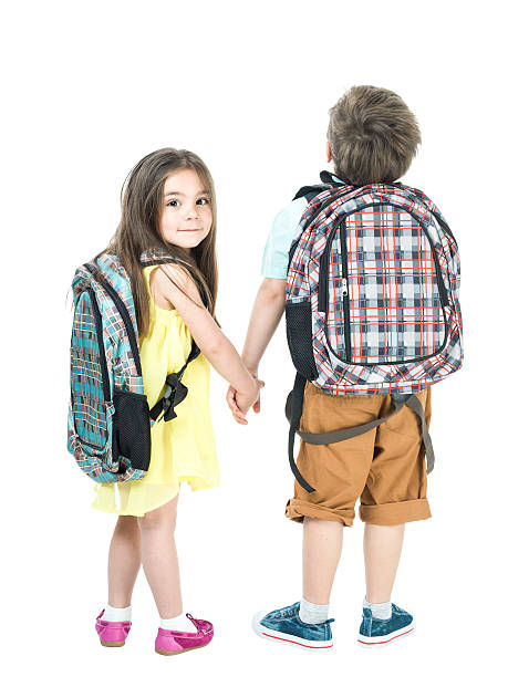 scuola piccola ragazza e ragazzo camminando mano nella mano - rear view family isolated child foto e immagini stock