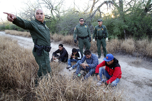 Fronton, Texas, USA - February 9, 2016:  A Border Patrol officer points towards where young Central Americans being taken into custody for illegally entering the United States by crossing the Rio Grande River in deep south Texas were caught.  Young Central Americans, most fleeing gang violence and poverty, continue to illegally enter the U.S. at near record levels.
