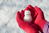 Mini snowman in girl hands with red wool gloves.