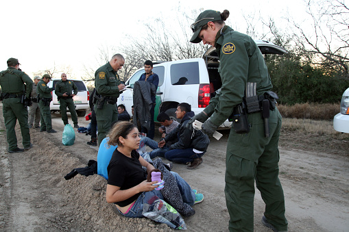 Fronton, Texas, USA - February 9, 2016: A young Salvadoran woman being taken into custody for illegally entering the United States by crossing the Rio Grande River in deep south Texas hands some of her belongings to a female Border Patrol agent. Young Central Americans, most fleeing gang violence and poverty, continue to illegally enter the U.S. at near record levels.