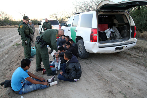 Fronton, Texas, USA - February 9, 2016: A Border Patrol agent removes handcuffs from a young Central American being taken into custody for illegally entering the United States by crossing the Rio Grande River in deep south Texas. Young Central Americans, most fleeing gang violence and poverty, continue to illegally enter the U.S. at near record levels.