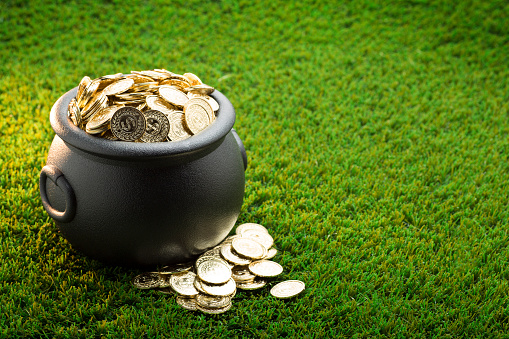 This is a close up photo of a large black pot of gold on the grass symbolizing St. Patrick's Day.