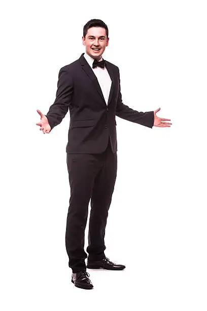 Cheerful young man in suit welcome sign and smiling while standing against white background.Showman concept.
