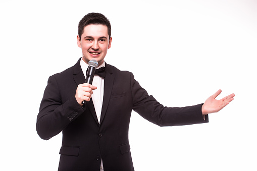 Young elegant talking man holding microphone and present invisible product. Isolated on white.Showman concept.