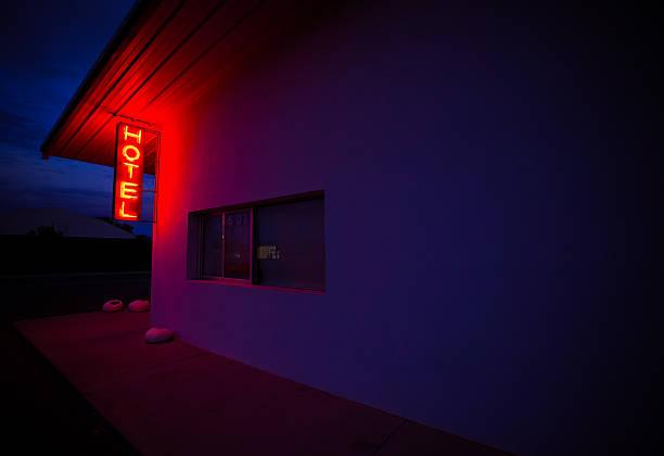 A red, neon Hotel sign illuminates the side of a wall in Marfa, Texas.