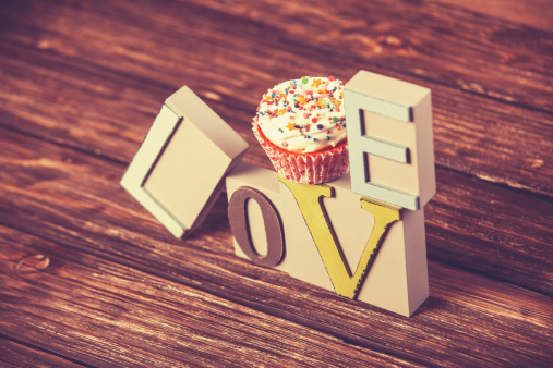 Cupcake and word Love on wooden table.