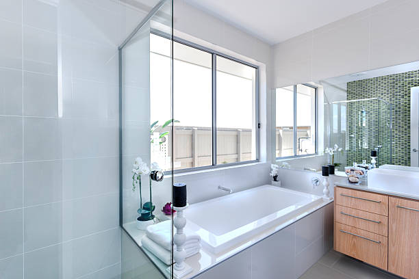 Custom beige toned master bathroom with double pedestal sinks and hot tub style tub in a beautiful suburban home.