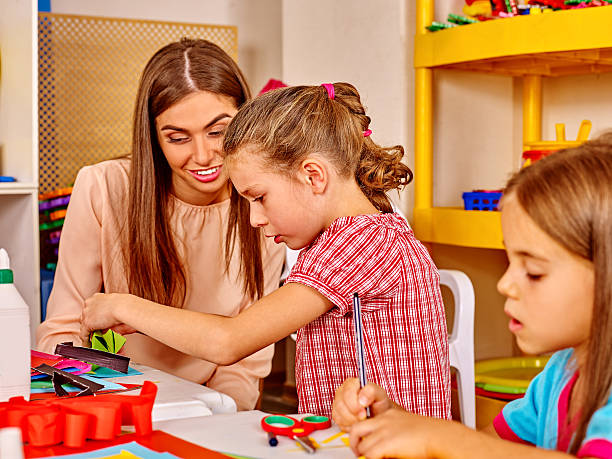 istock Teacher is teaching children how to make origami 510414102