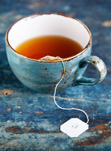 Cup of tea with teabag on blue textured background