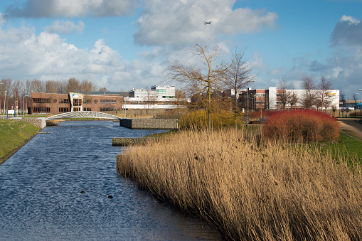 Nieuw Vennep, The Netherlands - February 16, 2014: Nieuw Vennep Zuid industrial and business estate in the Netherlands. A plane can be seen in the sky. In the foreground the landscaping of the estate is visible, including a lake.