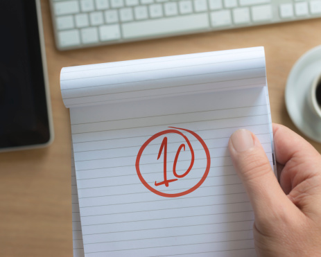 10 (a+) on a note pad with tablet,keyboard and coffee in backdrop