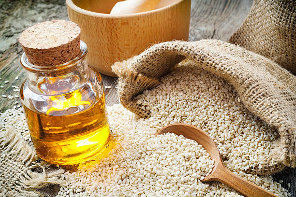 sesame seeds in sack and bottle of oil on  table stock photo