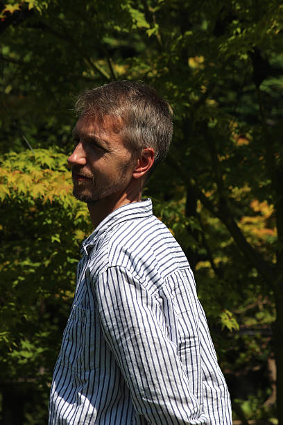 istock Man standing in sunny garden, with hands behind back 510442303